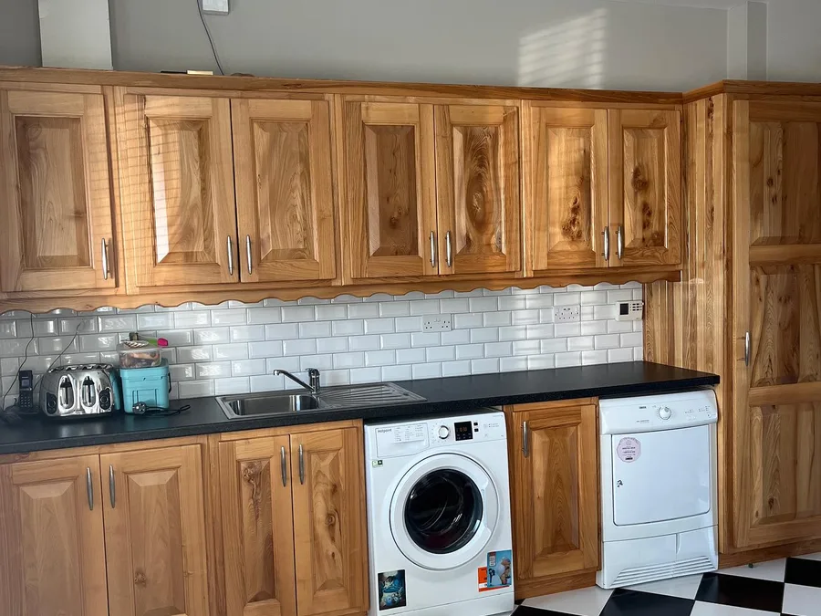 A kitchen before respraying, with dated units and a checkerboard floor