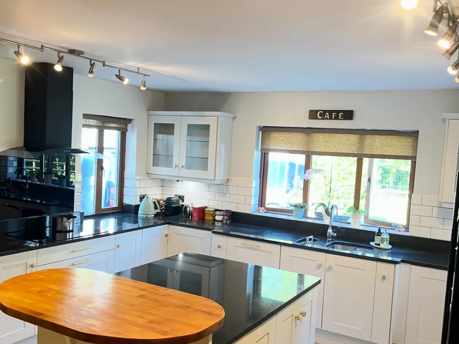 Kitchen resprayed in a soft shell white with an oval timber island top