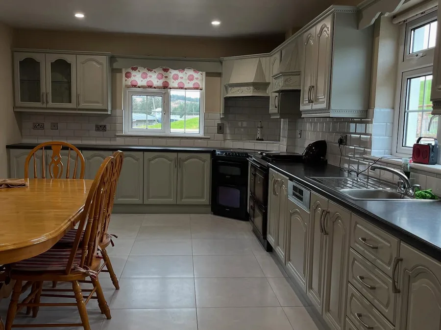 Kitchen resprayed in a pale stone colour, with a dining table and chairs