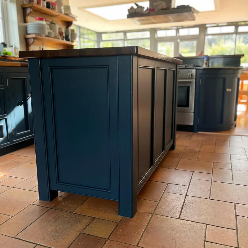 A hand-painted in-frame kitchen island in a deep blue-grey, over a terracotta tiled floor