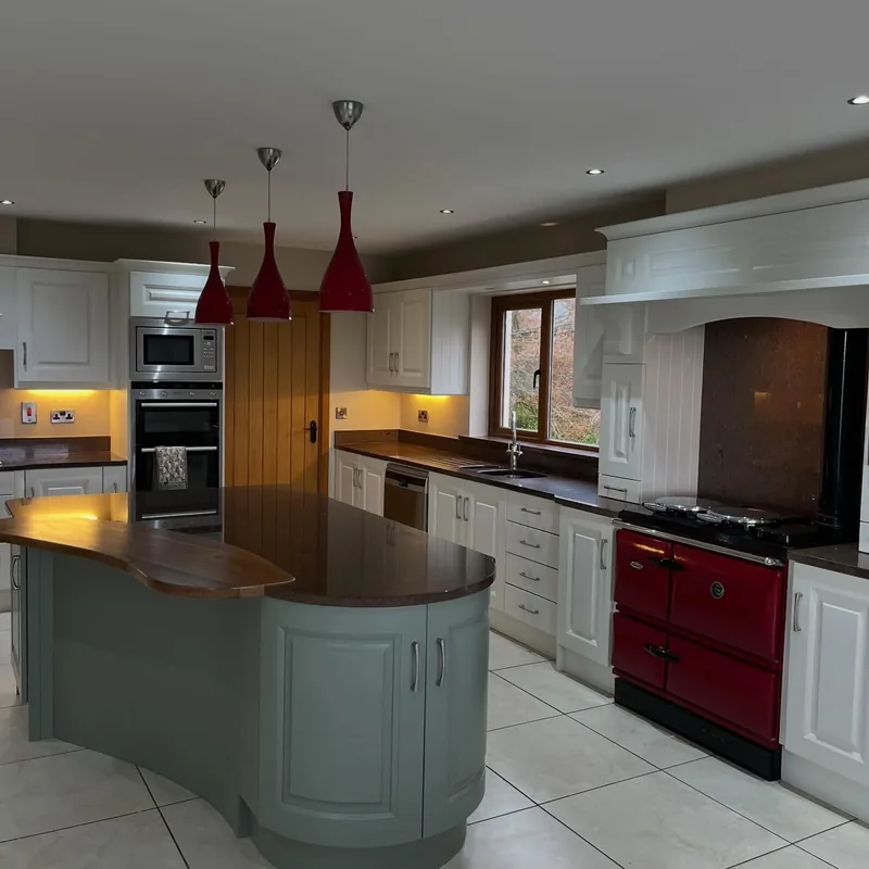 A curved kitchen island resprayed in Farrow and Ball Cardroom Green, with the units around it in a soft white